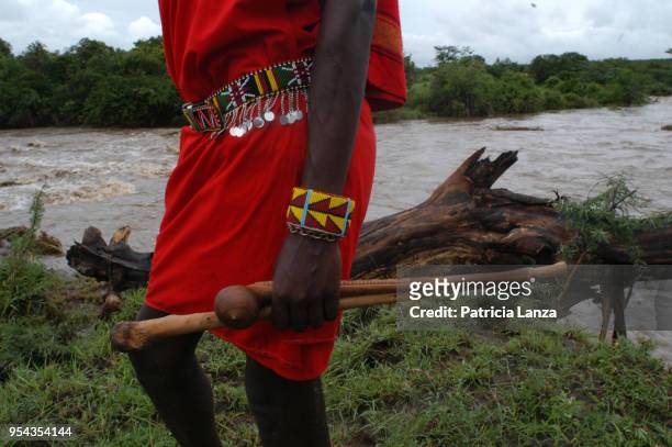 Close-up of a Maasai warrior, in traditional attire and beaded jewelry, as he holds a rungu , on a bank of the Mara River, Kenya, December 26, 2006.