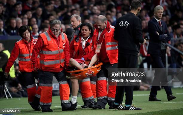 Medical staff carry Laurent Koscielny of Arsenal after he was injured during the UEFA Europa League semi final return match between Atletico Madrid...