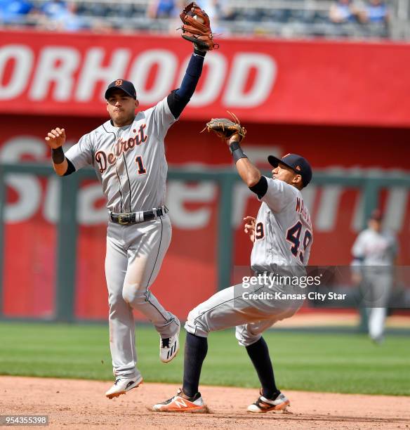 Detroit Tigers shortstop Jose Iglesias catches an infield chopper over shortstop Dixon Machado before throwing Kansas City Royals' Whit Merrifield...