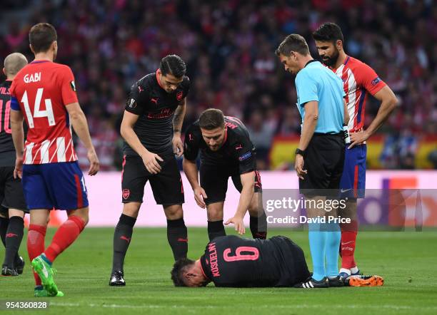 Laurent Koscielny of Arsenal is checked on by his team mates as he lies on the pitch injured during the UEFA Europa League Semi Final second leg...