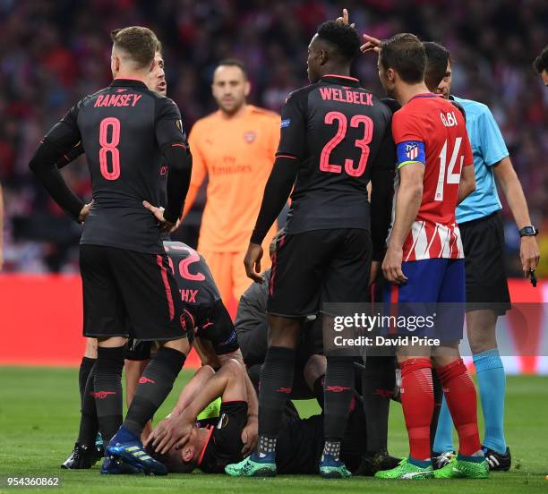 Laurent Koscielny of Arsenal is checked on by his team mates as he lies on the pitch injured during the UEFA Europa League Semi Final second leg...