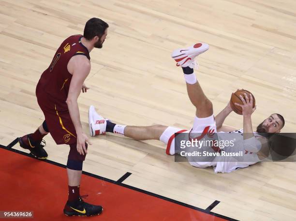 Toronto Raptors center Jonas Valanciunas looks to make a pass from the floor as Cleveland Cavaliers center Kevin Love stands over him as the Toronto...