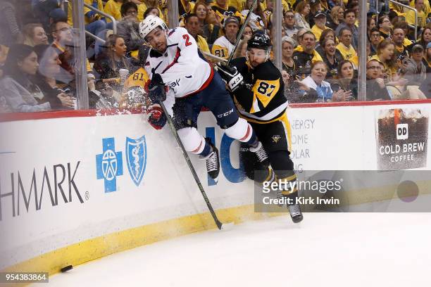 Matt Niskanen of the Washington Capitals and Sidney Crosby of the Pittsburgh Penguins slam into the boards while chasing after a loose puck during...