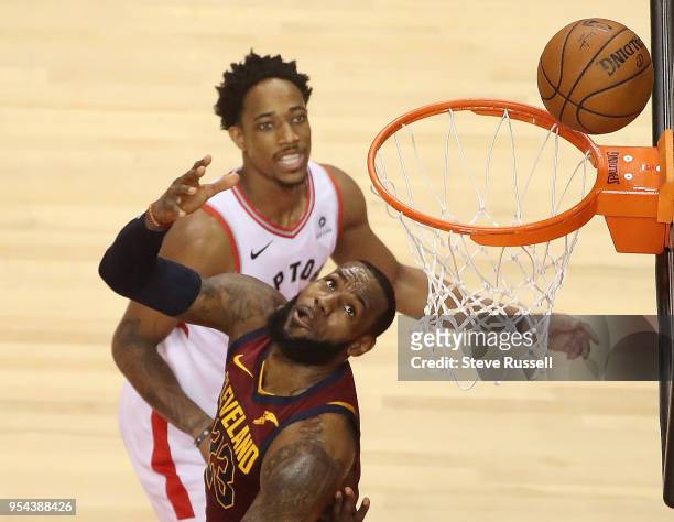 Cleveland Cavaliers forward LeBron James tries to bank the shot in off the glass as Toronto Raptors guard DeMar DeRozan looks on as the Toronto...