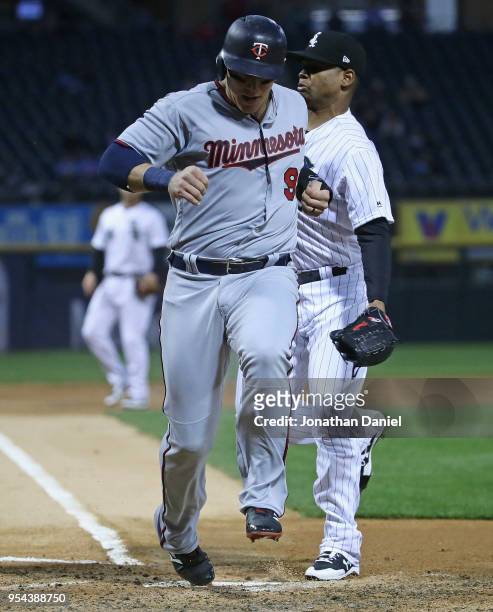Logan Morrison of the Minnesota Twins scores a run on a passed ball in the 3rd inning avoiding a collision with Reynaldo Lopez of the Chicago White...