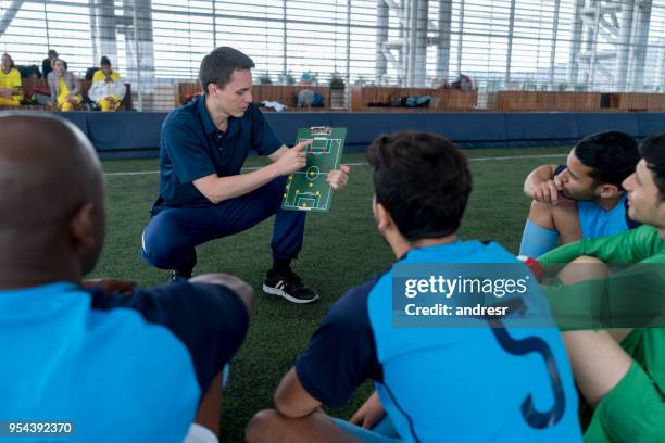 coach talking about strategy to his players pointing at a clipboard with magnets - football game plan stock pictures, royalty-free photos & images