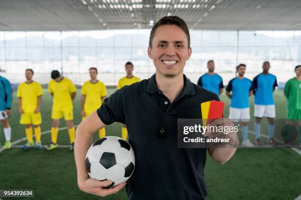 portrait of friendly referee holding a yellow and red card looking at camera smiling very happy - clubs playing card stock pictures, royalty-free photos & images