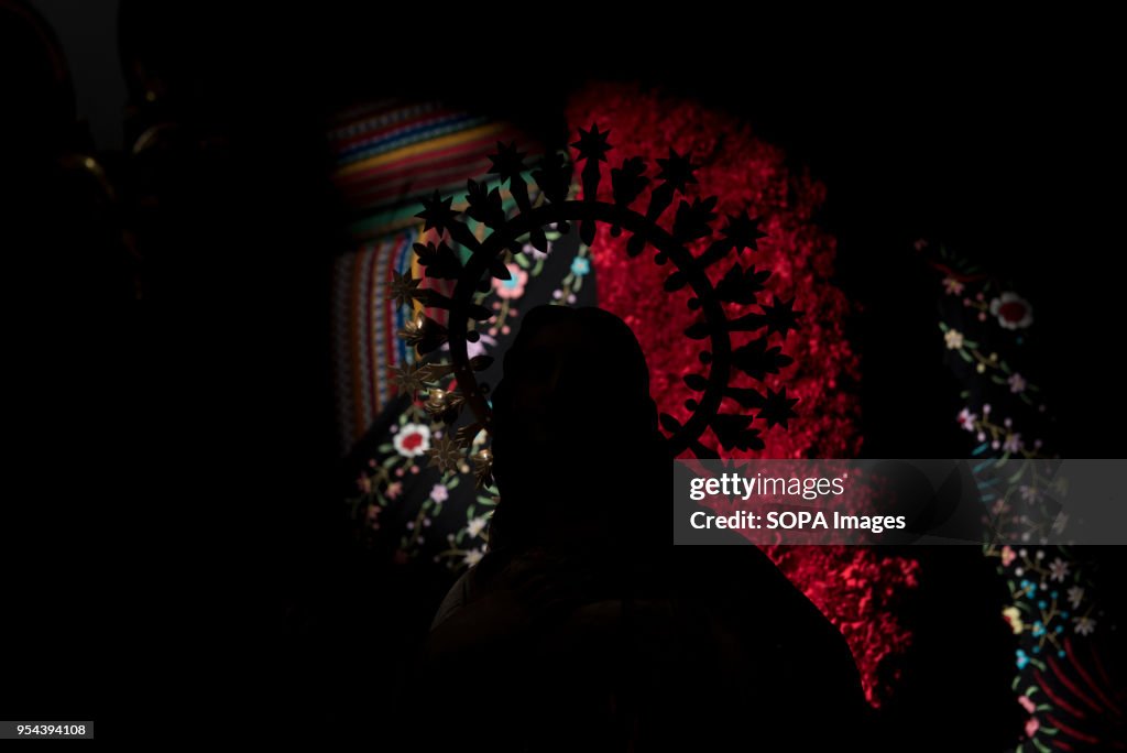 Silhouette of a statue in front of a cross decorated with...