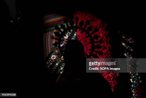 Silhouette of a statue in front of a cross decorated with carnations of Comendadoras de Santiago convent, seen the day before the Dia de las Cruces....