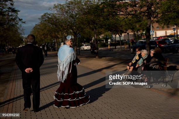 Woman wearing a typical flamenco dress seen walking with her husband. El día de la Cruz or Día de las Cruces is one of the most beautiful festivities...