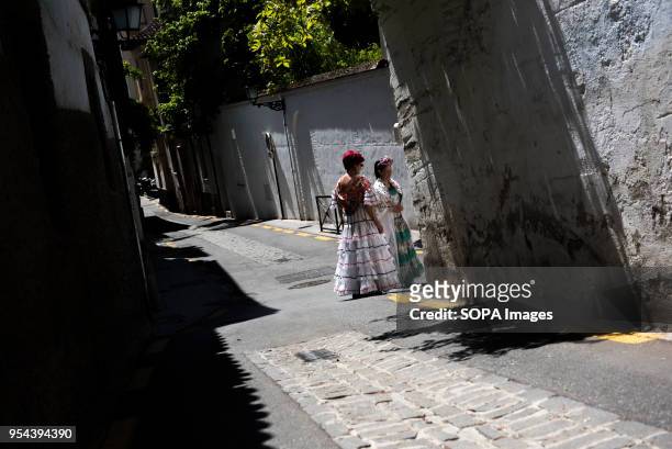 Two women wearing typical flamenco dress seen in a street of El Realejo neighbourhood during the Dia de las Cruces. El día de la Cruz. Día de las...