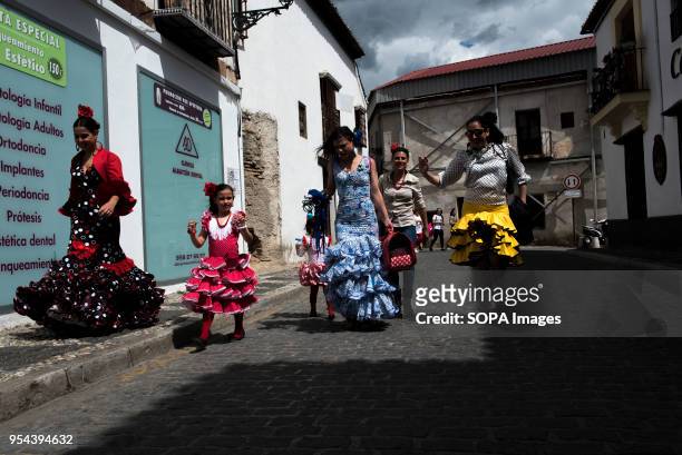 Women wearing typical flamenco dresses walking along the streets of Albaicin neighbourhood. El día de la Cruz or Día de las Cruces is one of the most...