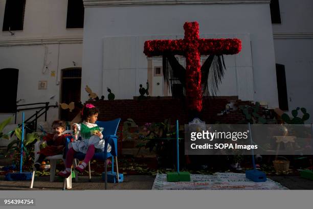 Two child sit in front of a crooss, during the Dia de la Cruz .El día de la Cruz or Día de las Cruces is one of the most beautiful festivities in...