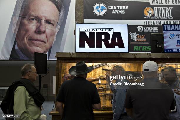 Attendees talk as they look over a display of guns inside the Kay Bailey Hutchison Convention Center ahead of the National Rifle Association annual...