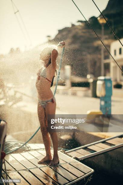 little girl taking shower on yacht stern - miljko stock pictures, royalty-free photos & images