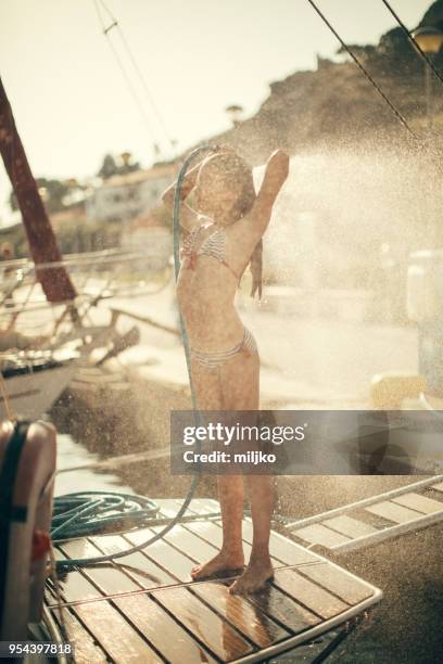little girl taking shower on yacht stern - miljko stock pictures, royalty-free photos & images