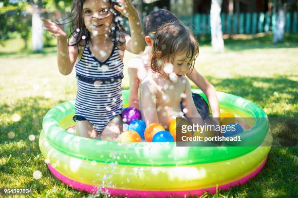 two children having fun in inflatable swimming pool - inflatable swimming pool stock pictures, royalty-free photos & images