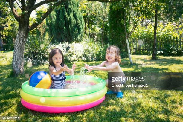 two children having fun in inflatable swimming pool - kids pool games stock pictures, royalty-free photos & images