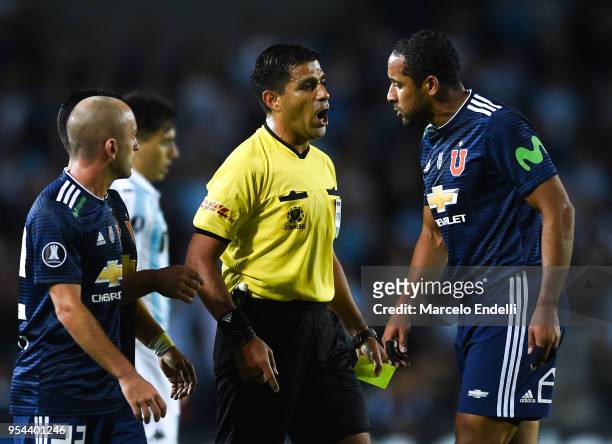Referee Enrique Caceres of Paraguay argues with Jean Beausejour of Universidad de Chile during a group stage match between Racing Club and...