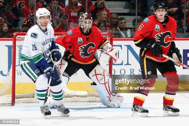 Curtis McElhinney and Dion Phaneuf of the Calgary Flames skate against Mikael Samuelsson of the Vancouver Canucks on December 27, 2009 at Pengrowth...