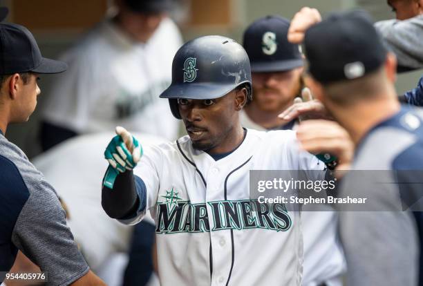 Dee Gordon of the Seattle Mariners celebrates in the dugout after scoring a run on a hit by Robinson Cano off of starting pitcher Sean Manaea of the...