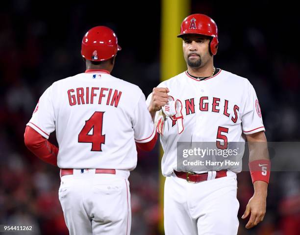 Albert Pujols of the Los Angeles Angels celebrates a double with first base coach Alfredo Griffin, for his 2999th career hit, during the second...