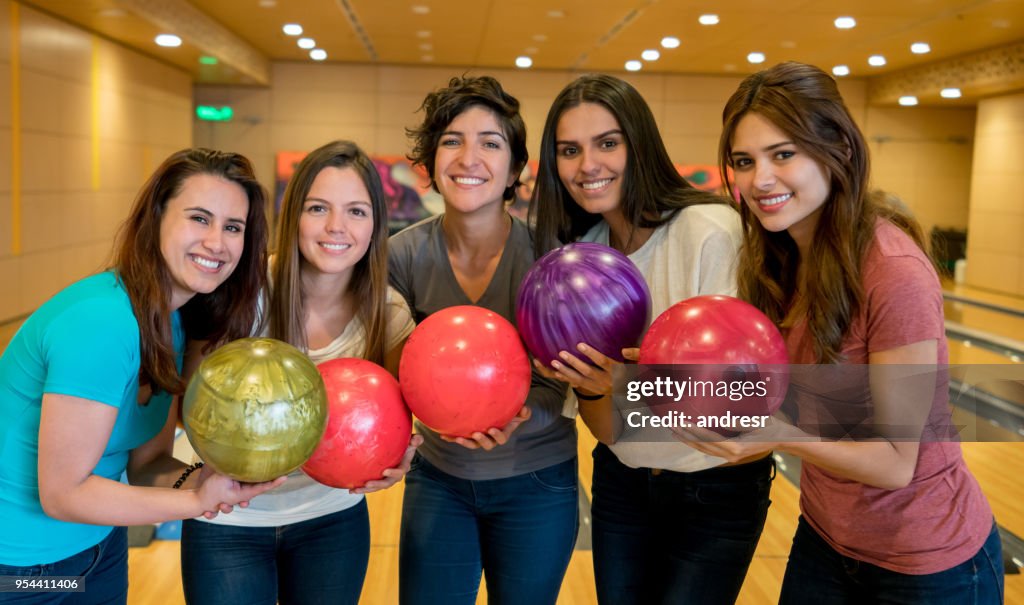 Felice gruppo di amiche che si divertono a giocare a bowling guardando la telecamera sorridente