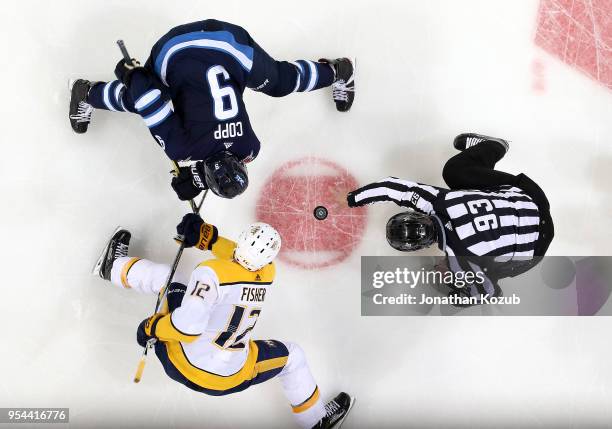 Linesman Brian Murphy drops the puck between Andrew Copp of the Winnipeg Jets and Mike Fisher of the Nashville Predators for a second period face-off...