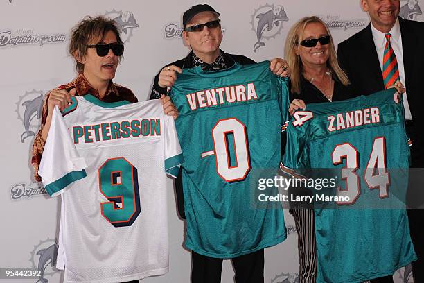 Tom Peterson, Rick Nielsen and Robin Zander of Cheap Trick pose on the orange carpet at the Miami Dolphins game at Landshark Stadium on December 27,...