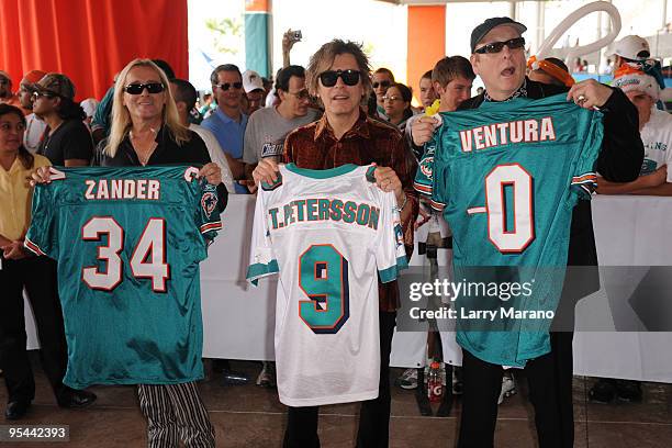 Tom Peterson, Rick Nielsen and Robin Zander of Cheap Trick pose on the orange carpet at the Miami Dolphins game at Landshark Stadium on December 27,...