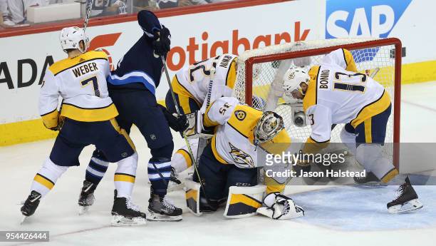 Adam Lowry of the Winnipeg Jets digs for the puck in the pad of Pekka Rinne of the Nashville Predators in Game Four of the Western Conference Second...