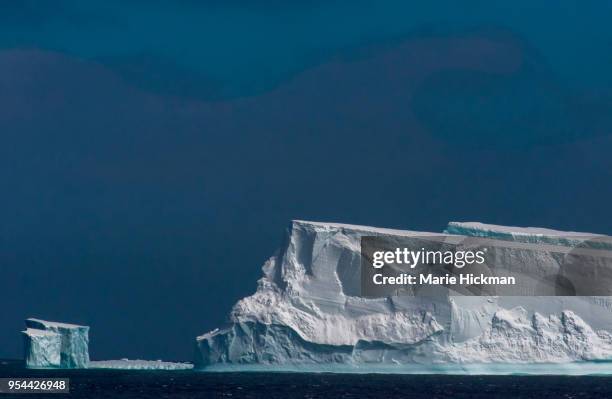 large iceberg and small iceberg behind it in antarctica. - marie hickman stock pictures, royalty-free photos & images