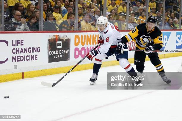 Dmitry Orlov of the Washington Capitals and Jake Guentzel of the Pittsburgh Penguins chase after a loose puck in Game Three of the Eastern Conference...