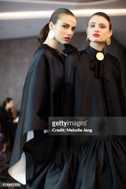 Models Tamar Gogoladze, Tekla Chijavadze in black dresses and coin earrings backstage at the Datuna F/W 18 show on May 3, 2018 in Tbilisi, Georgia.