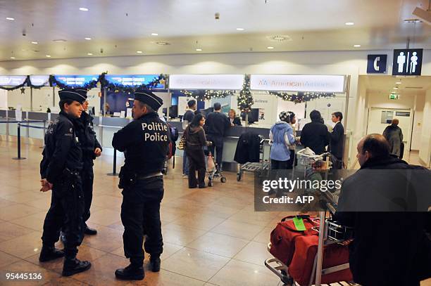 Belgian police officers stand opposite the American Airlines check-in counter at the Brussels Airport terminal, in Zaventem, on December 28, 2009....