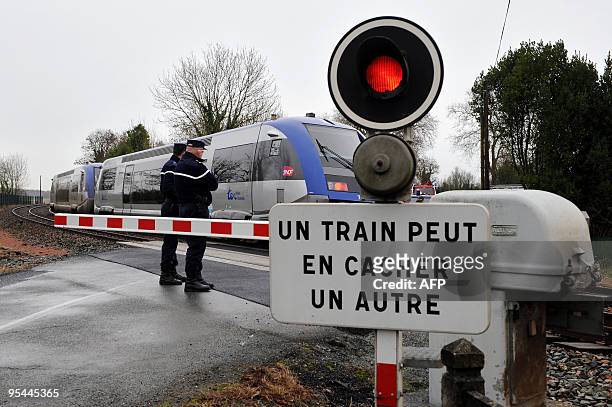 Des gendarmes surveillent un passage à niveau le 22 décembre 2009, où un TER est entré en collision avec une voiture, plus tôt dans la matinée, à...
