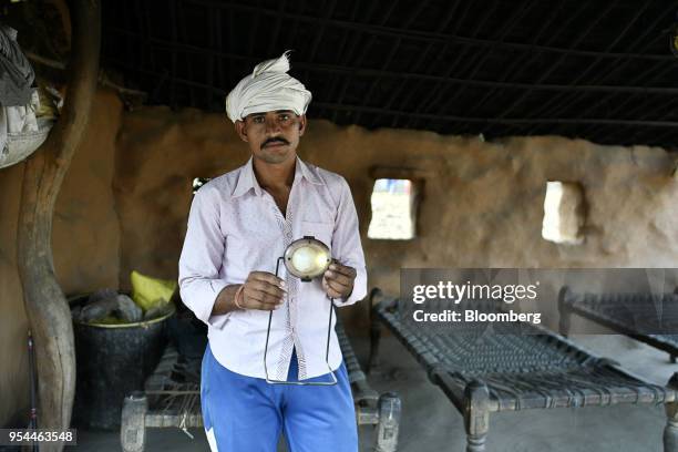 Man displays a light-emitting diode lamp for a photograph in Kraska village, Rajasthan, India, on Monday, April 16, 2018. The Indian government is...