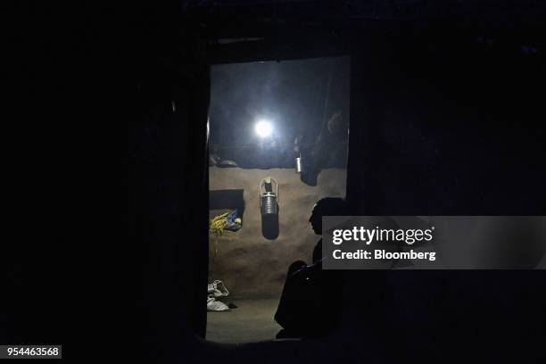 Woman sits in the doorway of a home illuminated by a single light-emitting diode lamp in Kraska village, Rajasthan, India, on Monday, April 16, 2018....