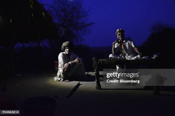 Men sit in a courtyard illuminated by a single light-emitting diode lamp at night in Kraska village, Rajasthan, India, on Monday, April 16, 2018. The...