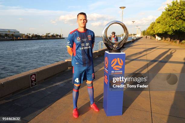 Nigel Boogaard of the Jets poses with the Hyundai A-League Champions Trophy at the Newcastle waterfront as Jets supprter rides by on his bike during...