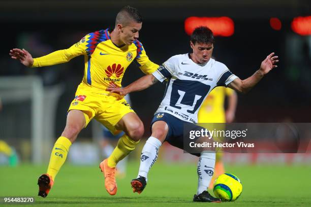 Matheus Uribe of America struggles for the ball with Matias Alustiza of Pumas during the quarter finals first leg match between Pumas UNAM and...