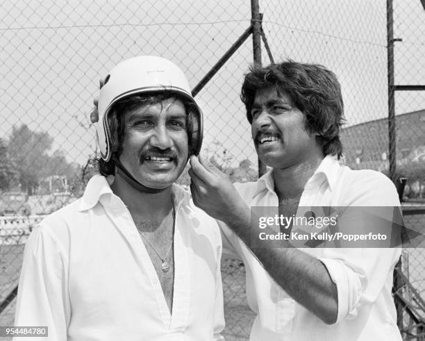 Pakistan batsman Sadiq Mohammad gets some help with his NEW batting helmet from teammate Javed Miandad during a training session before the 1st Test...