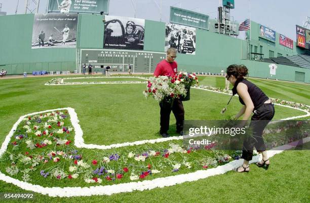 Vanessa Leyvas and James Giarrusso add the finishing touches to a floral number 9 placed on the outfield in honor of Baseball great Ted Williams for...