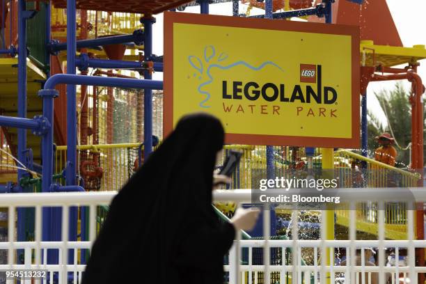 Woman wearing traditional dress watches the waterpark area at the Legoland Dubai theme park, operated by DXB Entertainments PJSC, in Dubai, United...