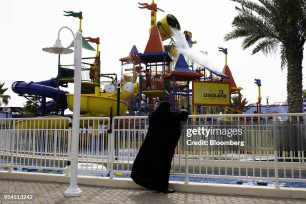 Woman wearing traditional dress watches the waterpark area at the Legoland Dubai theme park, operated by DXB Entertainments PJSC, in Dubai, United...