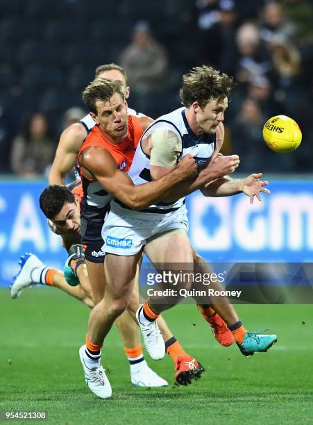 Jed Bews of the Cats handballs whilst being tackled by Matt De Boer of the Giants during the round seven AFL match between the Geelong Cats and the...