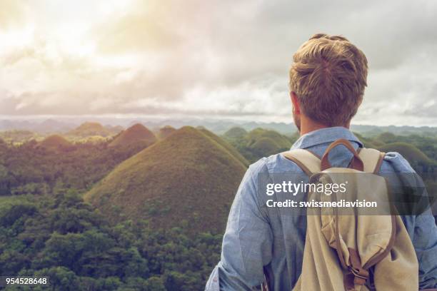 man traveling contemplates chocolate hills of bohol, philippines - bohol stock pictures, royalty-free photos & images