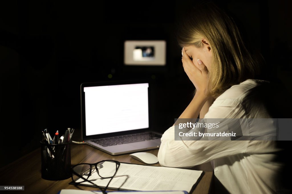 Mujer deprimida, trabajando con la computadora en la noche
