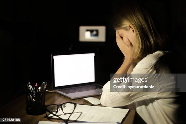 depressieve vrouw die werkt met de computer's nachts - threats stockfoto's en -beelden