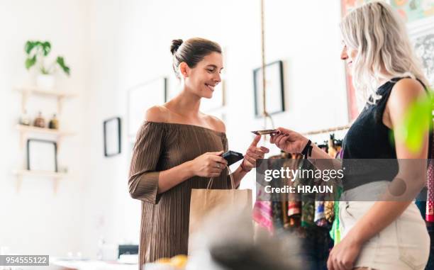 woman doing credit card purchase from saleswoman - clothes shop counter stock pictures, royalty-free photos & images